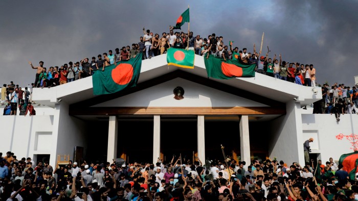 Anti-government protesters display Bangladesh’s national flag as they storm Prime Minister Sheikh Hasina’s palace in Dhaka